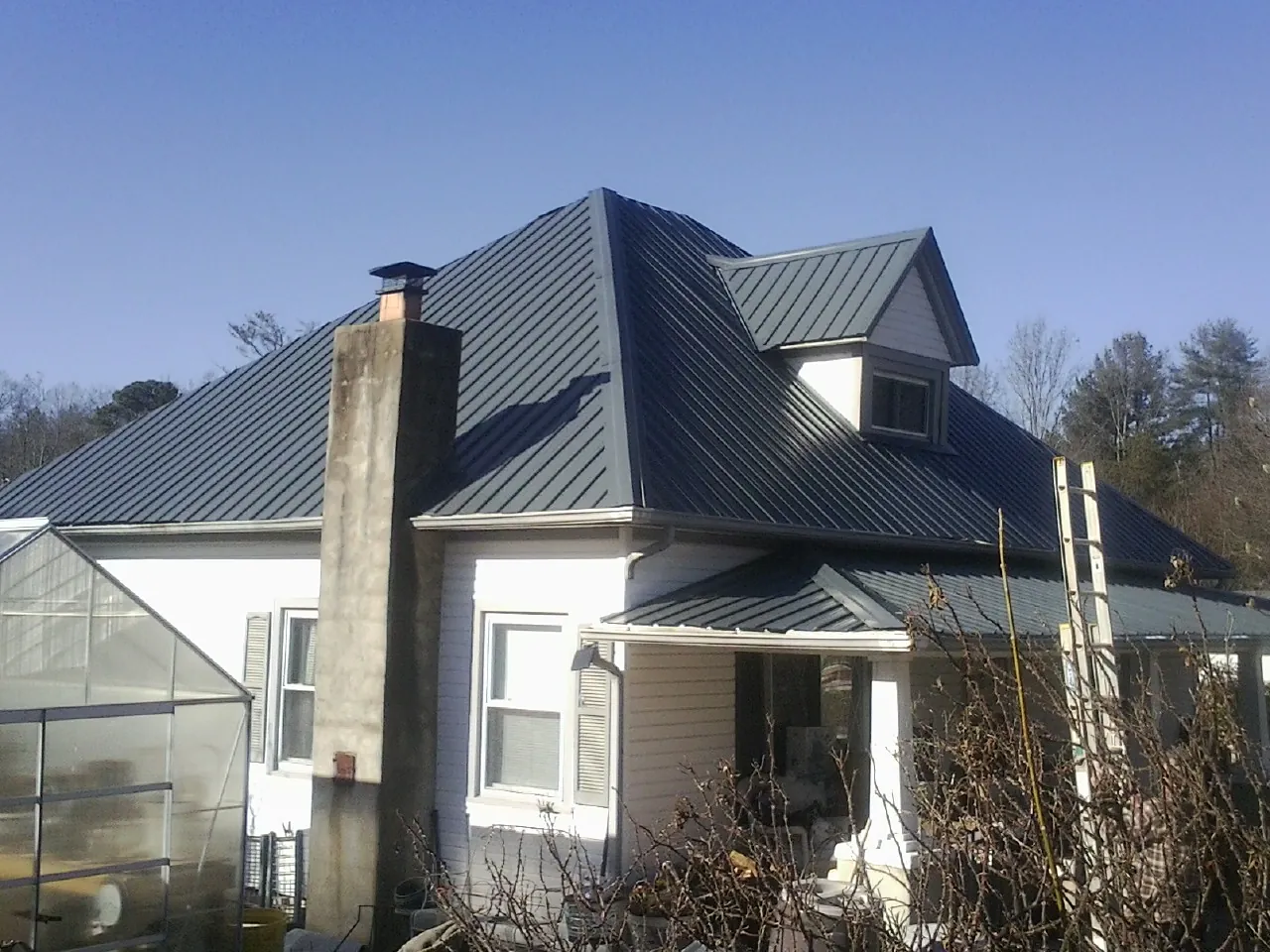 Dark blue standing seam metal roof on a white farmhouse with dormer — Slate & Tile Roof Repair by Roofing Brothers in Onondaga