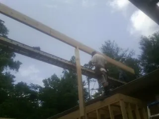 Carpenter setting a ridge beam over a new addition frame — Ice Dam Removal by Roofing Brothers in Onondaga