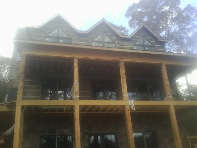 Dormers and porch framing on a large log home under construction — Roof Coating work by our crew in Onondaga