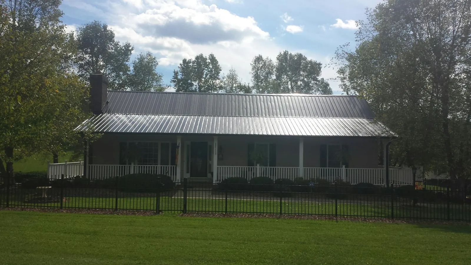 Gray metal roof on a brick ranch with a full width front porch — Gutter Guard Installation work by our crew in Onondaga