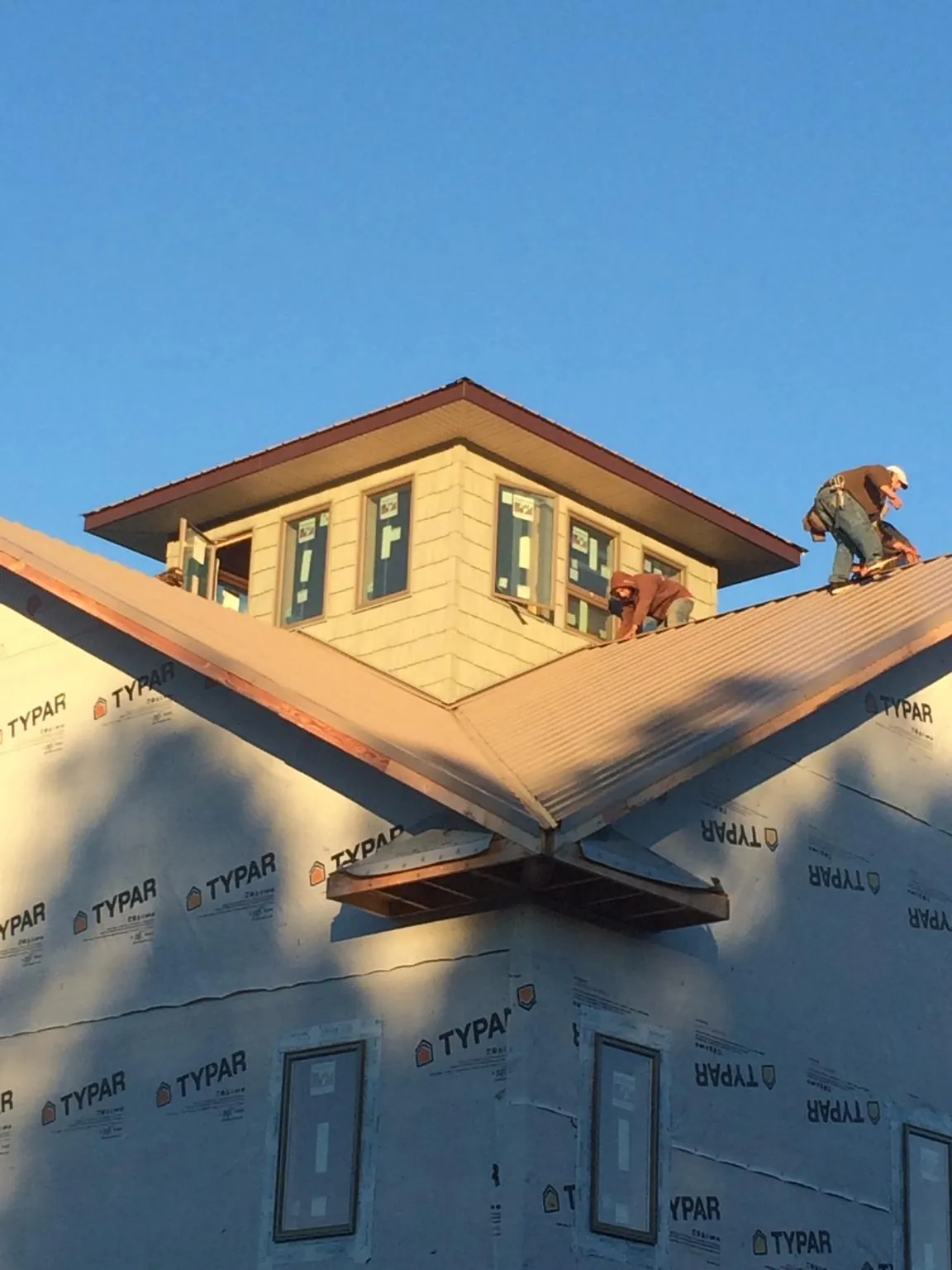 Roofers working around a rooftop cupola on a new metal roof at sunset — Roof Waterproofing in Onondaga by Roofing Brothers